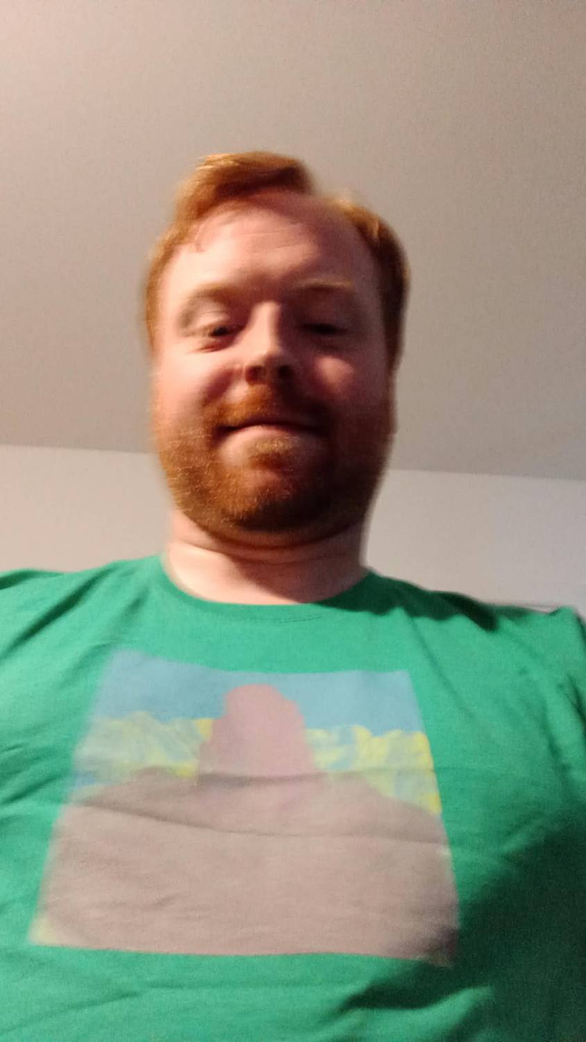 Scott, smiling, wearing a green t-shirt printed with his own painting